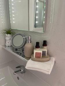 a bathroom sink with a mirror and cosmetics on it at contemporary quiet countryside retreat in Horsley