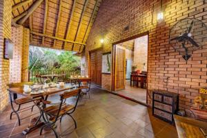 uma sala de jantar com mesa e cadeiras e uma parede de tijolos em Dreamfields Guesthouse em Hazyview