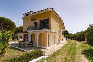 a yellow house with a balcony and a table at Lenna's Villas Zante in Vasilikos