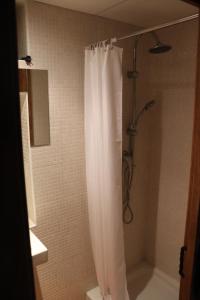 y baño con ducha con cortina blanca. en Apartamentos Las Buganvillas, en Cáceres