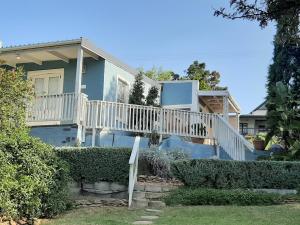 a blue house with a white deck and stairs at Pascal's of Napier in Napier