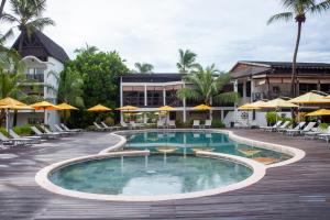 una piscina en un complejo con sillas y sombrillas en Royal Beach Hôtel en Ambatoloaka
