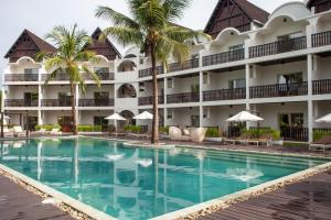 a pool in front of a hotel with palm trees at Royal Beach Hôtel in Ambatoloaka