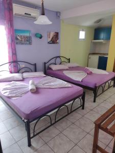 three beds in a room with purple mattresses at Hotel Ifigenia Paralia Katerinis plaz in Paralia Katerinis