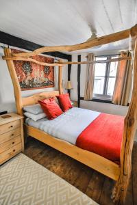 um quarto com uma cama de dossel em madeira com almofadas vermelhas em Fisherman's Cottage! em Hastings