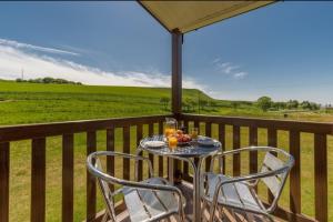 a table and chairs on a balcony with a view of a field at COASTAL CARAVAN ELIE sleeps 6 in Elie