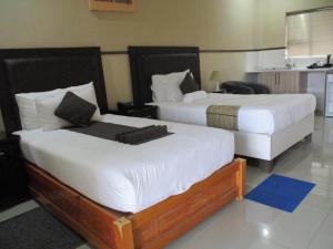 2 camas en una habitación de hotel con sábanas blancas en River View Villa Self Catering, en Francistown