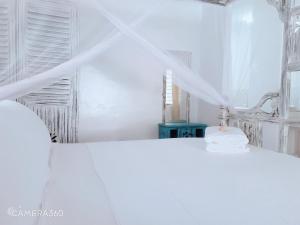 a white room with a bed and a mirror at Diwani Cottage in Malindi