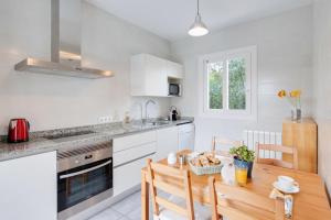 cocina con armarios blancos y mesa de madera en Casa Aina, en Cala Bona