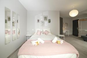 a white bedroom with a large bed with pink pillows at Duplex République in Clermont-Ferrand