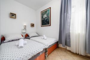 two twin beds in a room with a window at BOŽICA House with apartments in Murine