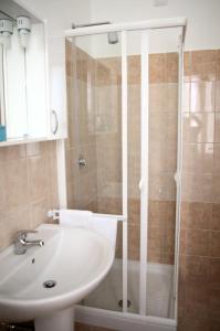 W łazience znajduje się biała umywalka i prysznic. w obiekcie Foresteria Roma Esercito della Salvezza w Rzymie