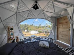 a bedroom in a dome tent with a large window at The Haus at Khaokho in Khao Kho