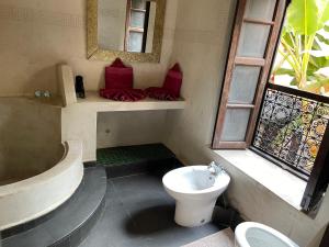a bathroom with a toilet and a sink and a window at Riad Bamileke in Marrakech