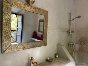 a bathroom with a mirror and a tub and a sink at Riad Bamileke in Marrakech