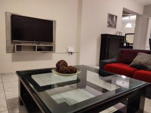 a living room with a glass coffee table and a tv at Euphoria Apartment in Nafplio