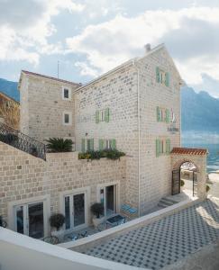a large brick building with green shuttered windows at Hotel Libertas in Kotor