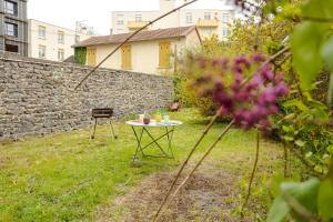 a table and chair in a yard with a stone wall at Duplex République in Clermont-Ferrand