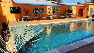 Una piscina con mesas y sillas al lado de un edificio. en Le Passamainty Lodge, en Mamoudzou