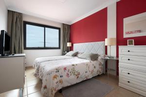 1 dormitorio con cama y pared roja en Trevina 31-2 en Puerto de la Cruz