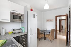 a kitchen with a white refrigerator and a table at Villa Hibiscus in Playa Blanca