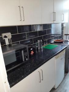 a kitchen with white cabinets and a black counter top at Rhyl Aparthotels in Rhyl