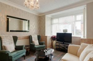 a living room with a couch and chairs and a tv at Stoneleigh Hotel in Skegness
