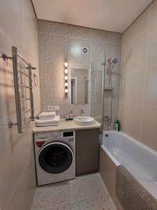 a bathroom with a washing machine next to a bath tub at Квартира в самом центре in Almaty