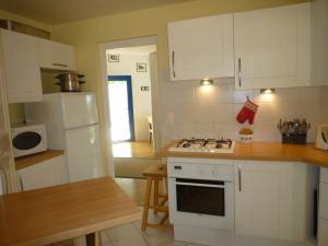 een keuken met witte kasten en een fornuis met oven bij Villa Spacieuse avec Beau Jardin, Wifi, Port a 500m, Trinite sur Mer in La Trinité-sur-Mer