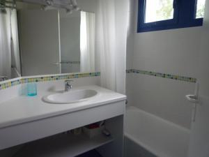 La salle de bains est pourvue d'un lavabo, d'une baignoire et d'un miroir. dans l'établissement Villa Spacieuse avec Beau Jardin, Wifi, Port a 500m, Trinite sur Mer, à La Trinité-sur-Mer