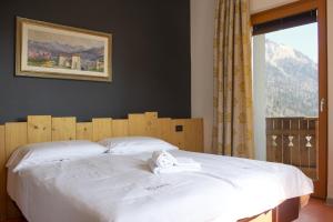 a bedroom with a large white bed with a window at Albergo Croce d'Aune in Pedavena