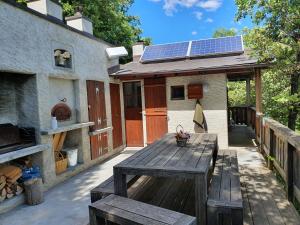 a patio with a wooden table and a house with solar panels at La Terrasse in Fully