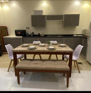 uma mesa de jantar com cadeiras e uma cozinha em شالية لورينزو em Buraydah