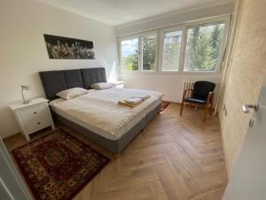 a bedroom with a bed and a chair and windows at Hidden Gem in Belgrade