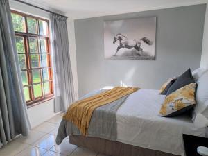 1 dormitorio con 1 cama y una foto de un caballo en Faithlands Self-Catering Cottages, en Port Elizabeth