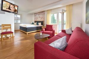 Una sala de estar con un sofá rojo y una cama. en Thermen Appartements Gabriela, en Bad Krozingen
