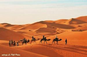 a group of people riding horses in the desert at Hotel Riad Le Petit Prince in Merzouga
