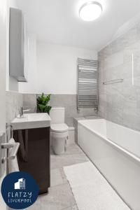 a bathroom with a tub and a toilet and a sink at FLATZY - Quiet Sefton Park Luxury Apartment in Liverpool