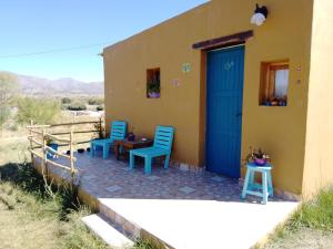 a house with two chairs and a blue door at El Cardón,monoambiente en el campo in Humahuaca