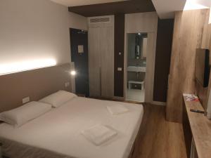 una camera da letto con un grande letto bianco e una televisione di Albergo Baschera a Fagagna