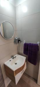 y baño con lavabo, espejo y toallas púrpuras. en Bingus en Mar del Plata