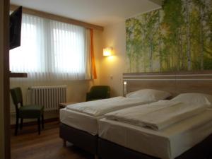 a bedroom with two beds and a large window at Berghotel Glockenberg in Sankt Andreasberg