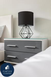 a bed with a dresser with a lamp on it at FLATZY - Quiet Sefton Park Luxury Apartment in Liverpool