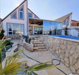 a house with a stone retaining wall and a yard at Caspian Villa Merdekan in Şüvǝlǝn