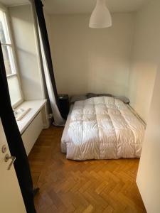 Apartment in Stockholm, 48m2 in Mariatorget Södermalm في ستوكهولم: غرفة نوم بسرير ابيض وارضية خشبية