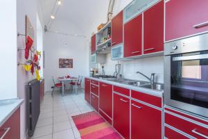 eine Küche mit roten Schränken, einer Spüle und einem Tisch in der Unterkunft San Salvario Family Apartment by Wonderful Italy in Turin