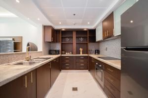 a large kitchen with wooden cabinets and stainless steel appliances at Luton Vacation Homes - Park Island, marina view-Dubai Marina-60AB5 in Dubai