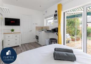 um quarto com uma cama branca e uma cozinha em Flatzy - Charming Garden Annexe in Aigburth with Kitchenette em Liverpool