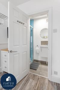 a bathroom with a white door and a mirror at Flatzy - Charming Garden Annexe in Aigburth with Kitchenette in Liverpool