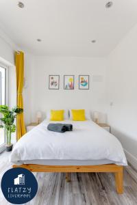 1 dormitorio con 1 cama con sábanas blancas y almohadas amarillas en Flatzy - Charming Garden Annexe in Aigburth with Kitchenette en Liverpool